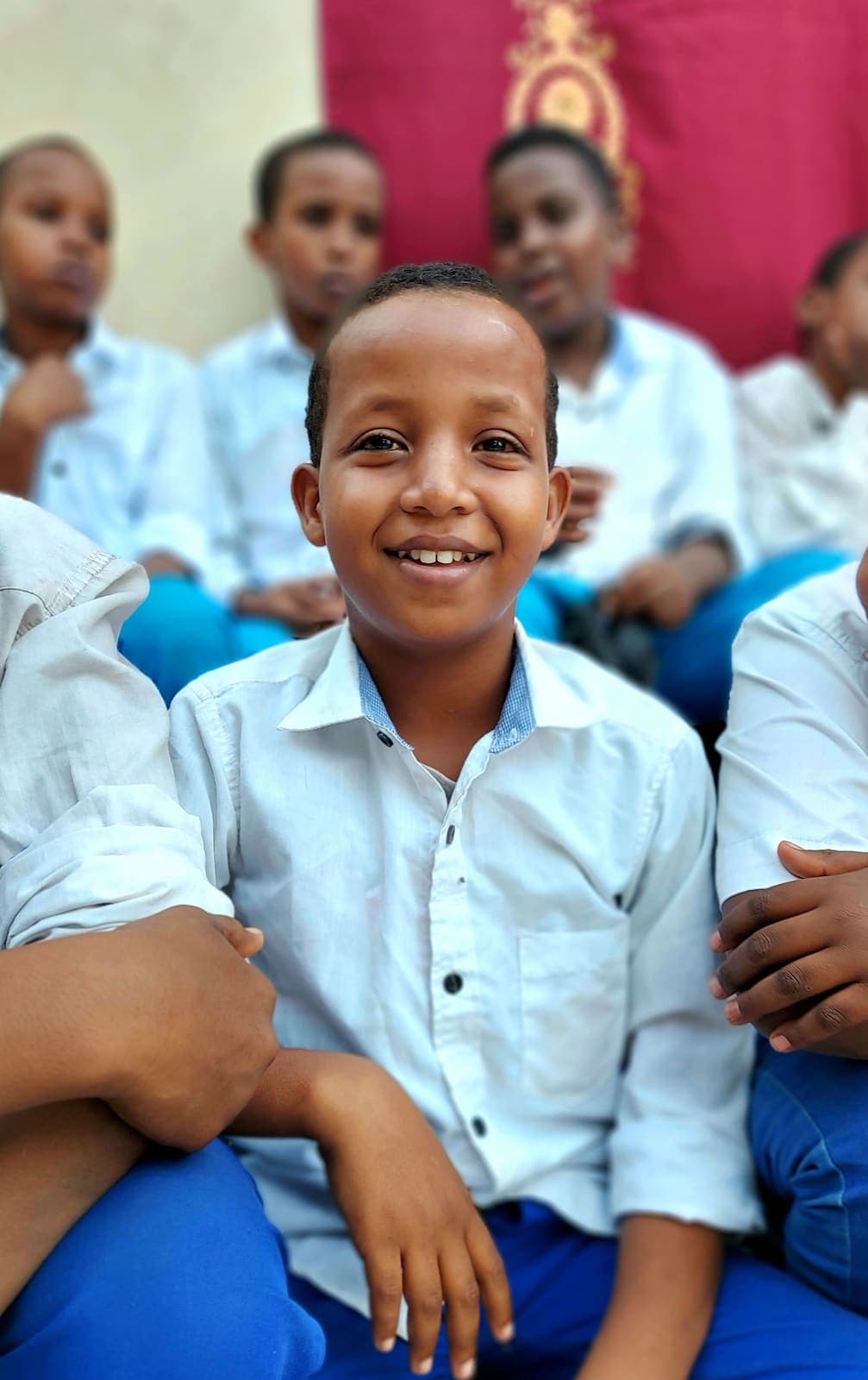 A smiling schoolboy in uniform standing with his classmates