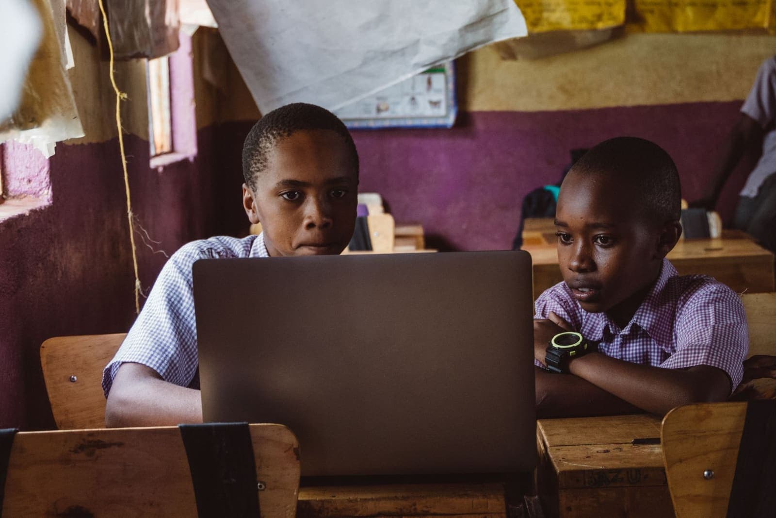 Two pupils in school uniform working together on a laptop