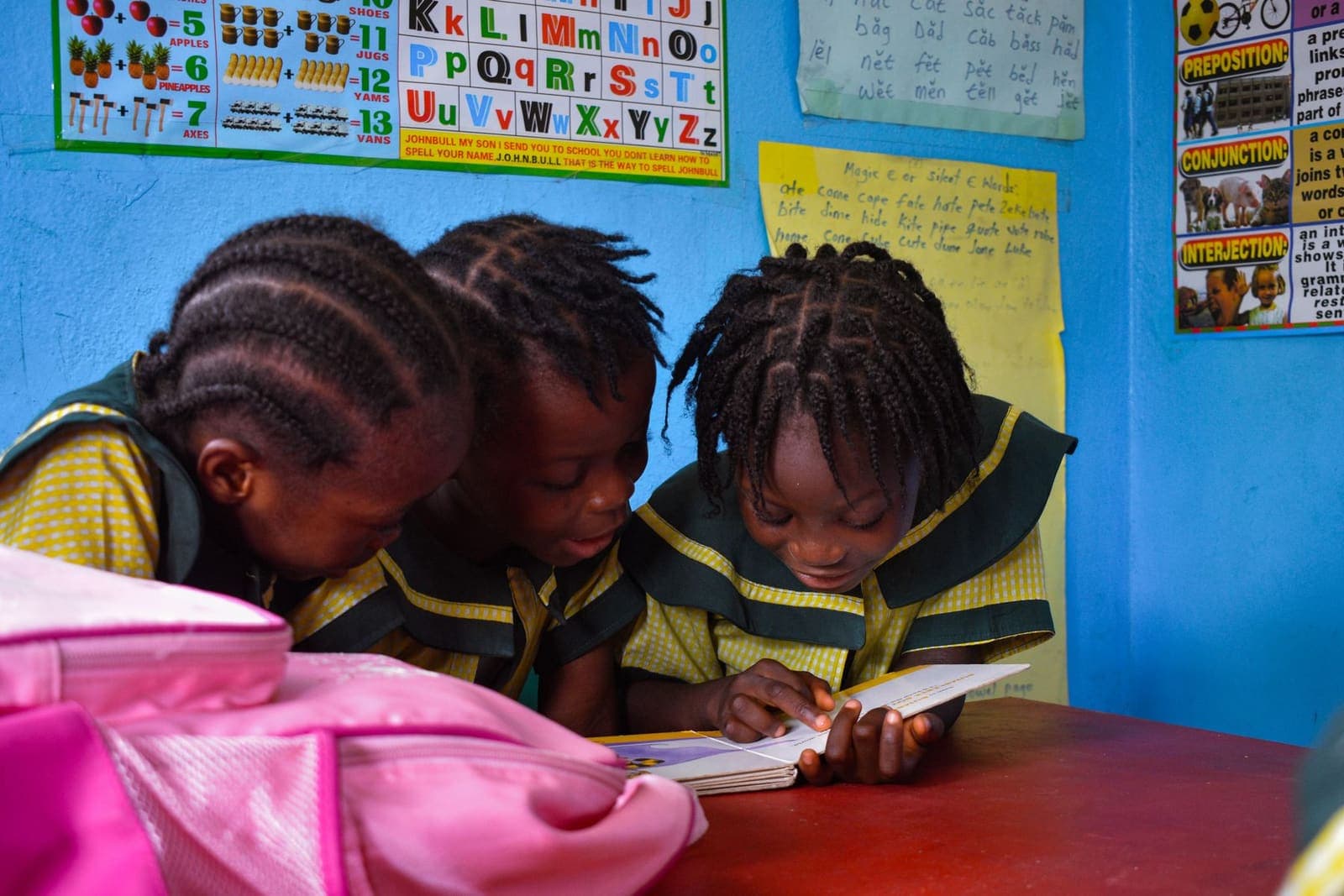 Three pupils reading books together at a school library table
