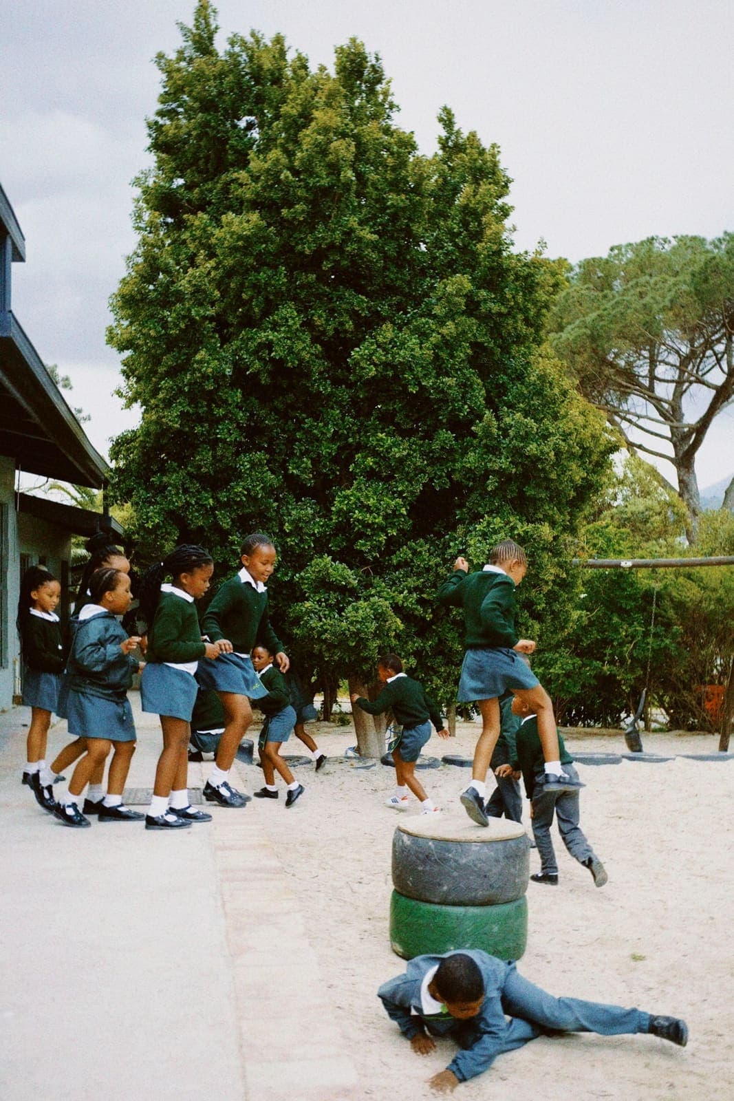Pupils in uniform playing together in a shaded schoolyard