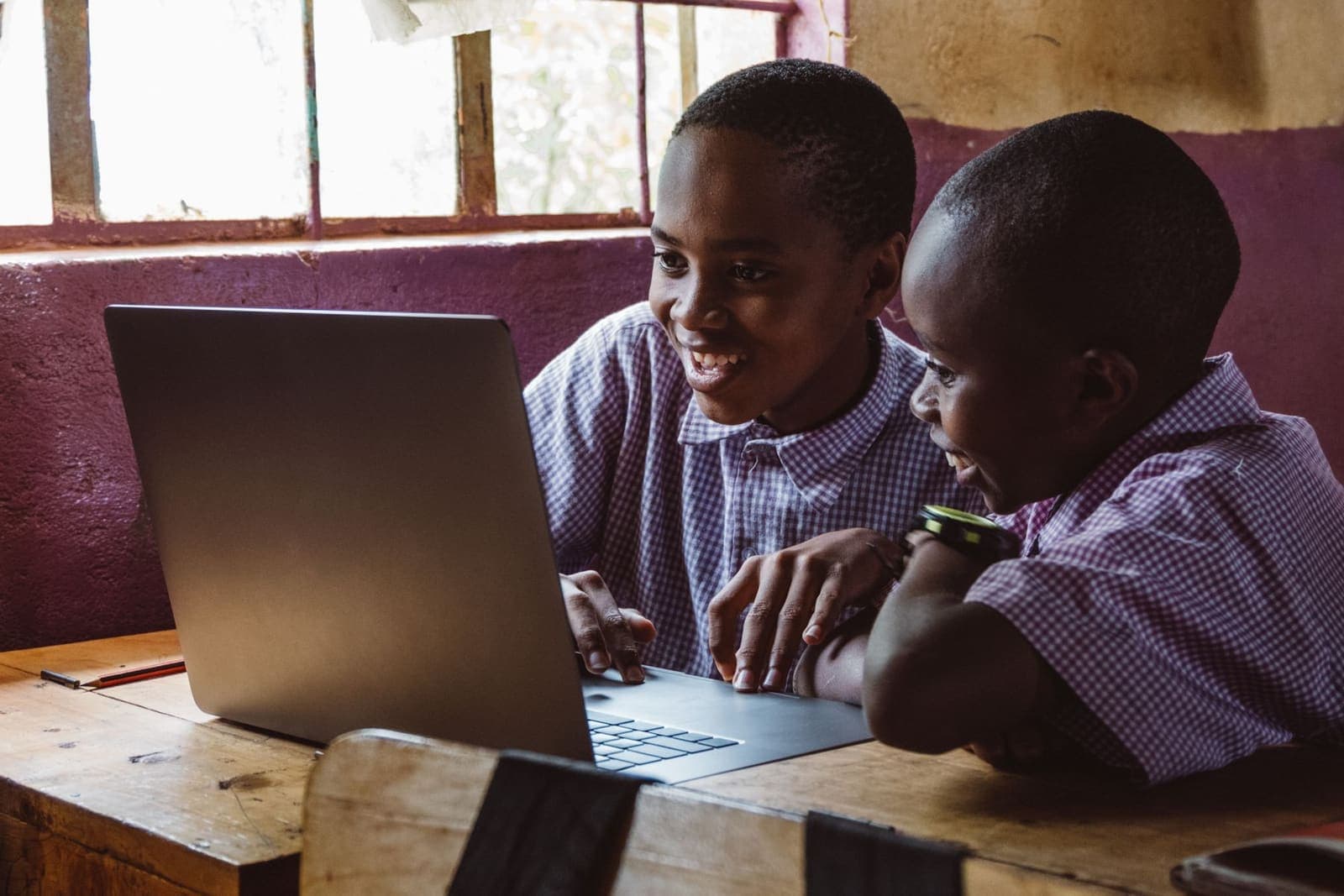 Two pupils in school uniform learning together on a laptop