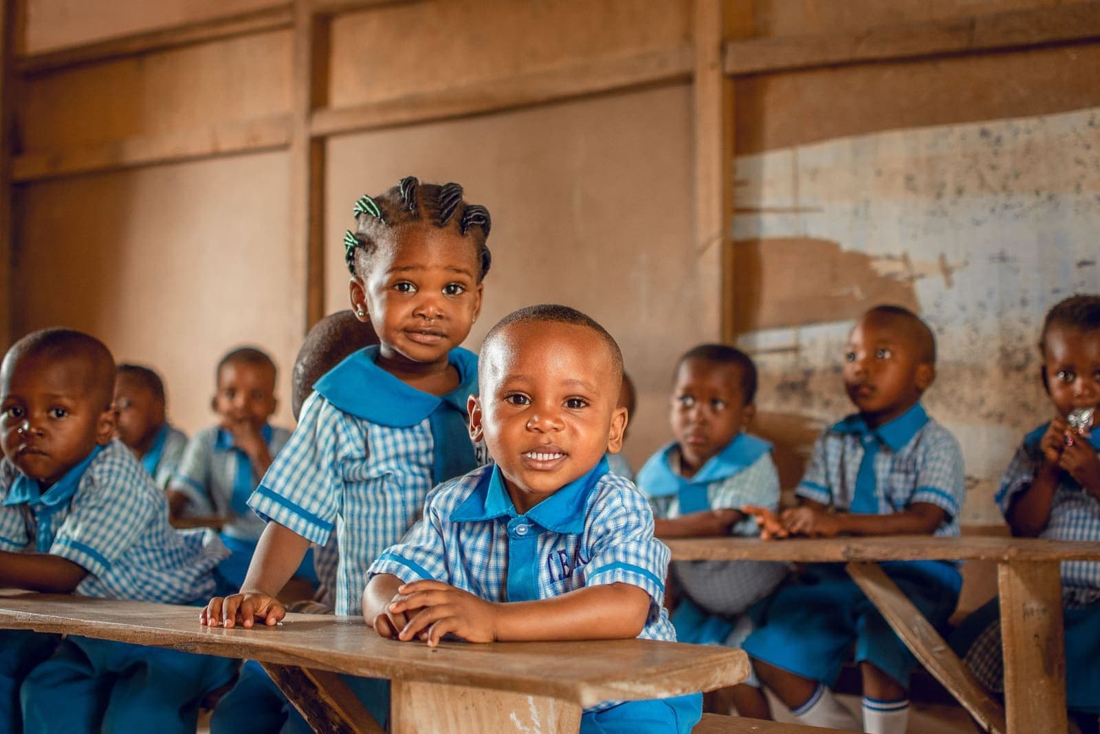 Happy pupils in blue uniforms seated together in a bright classroom