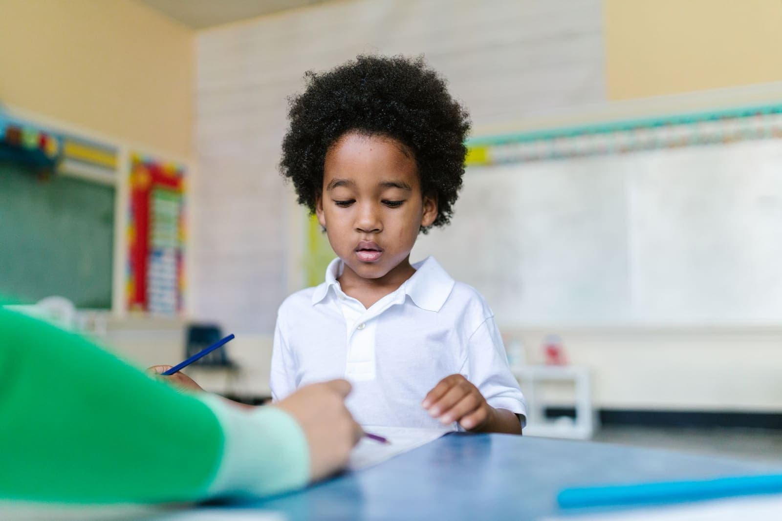A young boy concentrating on a learning activity in a bright kindergarten classroom